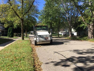 Rochester street sweeper removes leaves from a roadway and displays one of the outreach messages about debris prevention