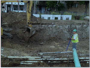 This picture shows a tracked backhoe and hand laborer in infiltration area during excavation