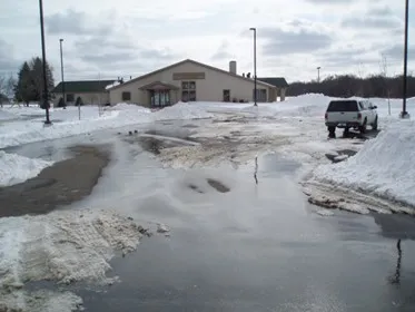 Photograph showing snow meltwater spreading across a parking lot. 