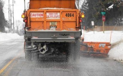 View of salt spreader on the back of a working snowplow.